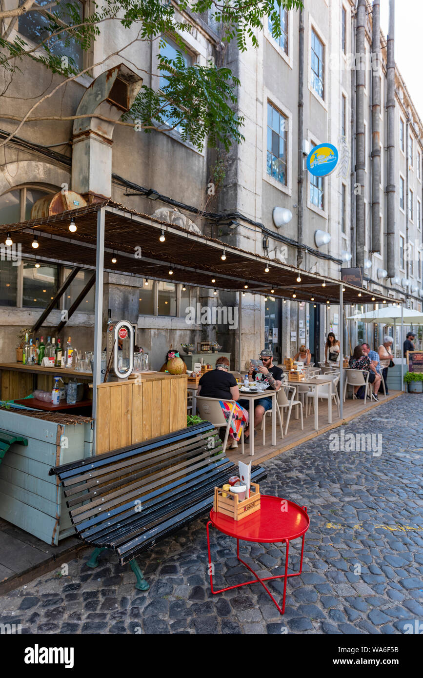 Lisbonne, Portugal - 15 juillet, 2019 : terrasse restaurant, LX Factory street market sous le pont suspendu Ponte 25 de Abril. Banque D'Images