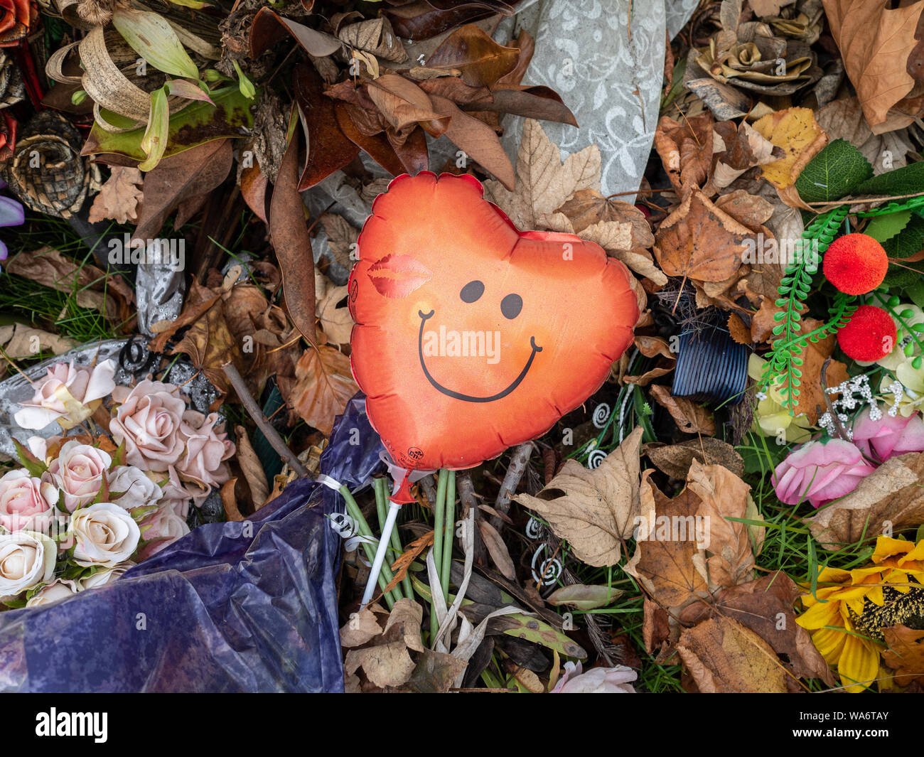 Un ballon coeur rouge avec smiley face entre fading tributs floraux, tir à la mosquée au lieu commémoratif à Christchurch, Nouvelle-Zélande Banque D'Images