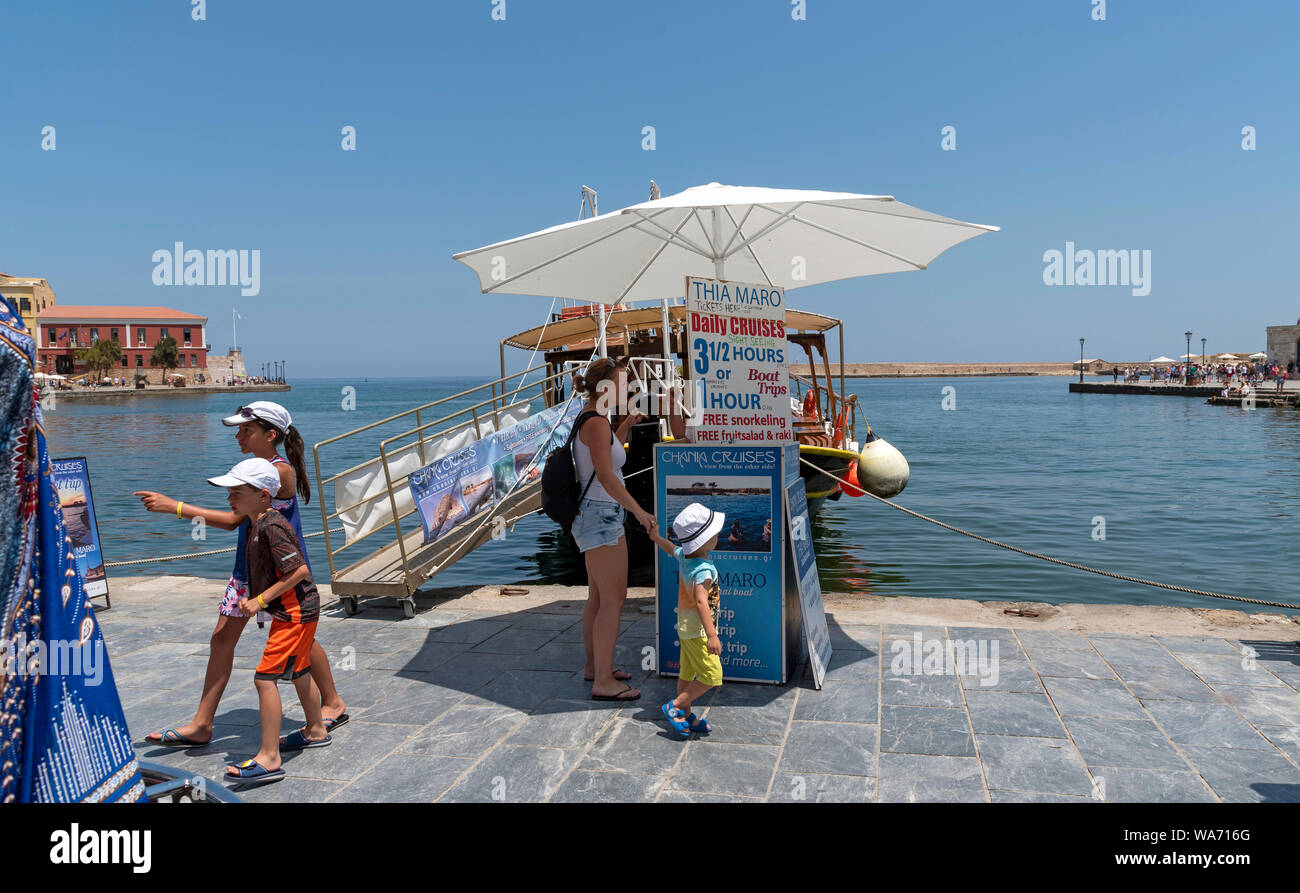 La Canée, Crète, Grèce. Femme et enfant faire une réservation pour aller sur un voyage en bateau à partir du vieux port vénitien de La Canée. Banque D'Images
