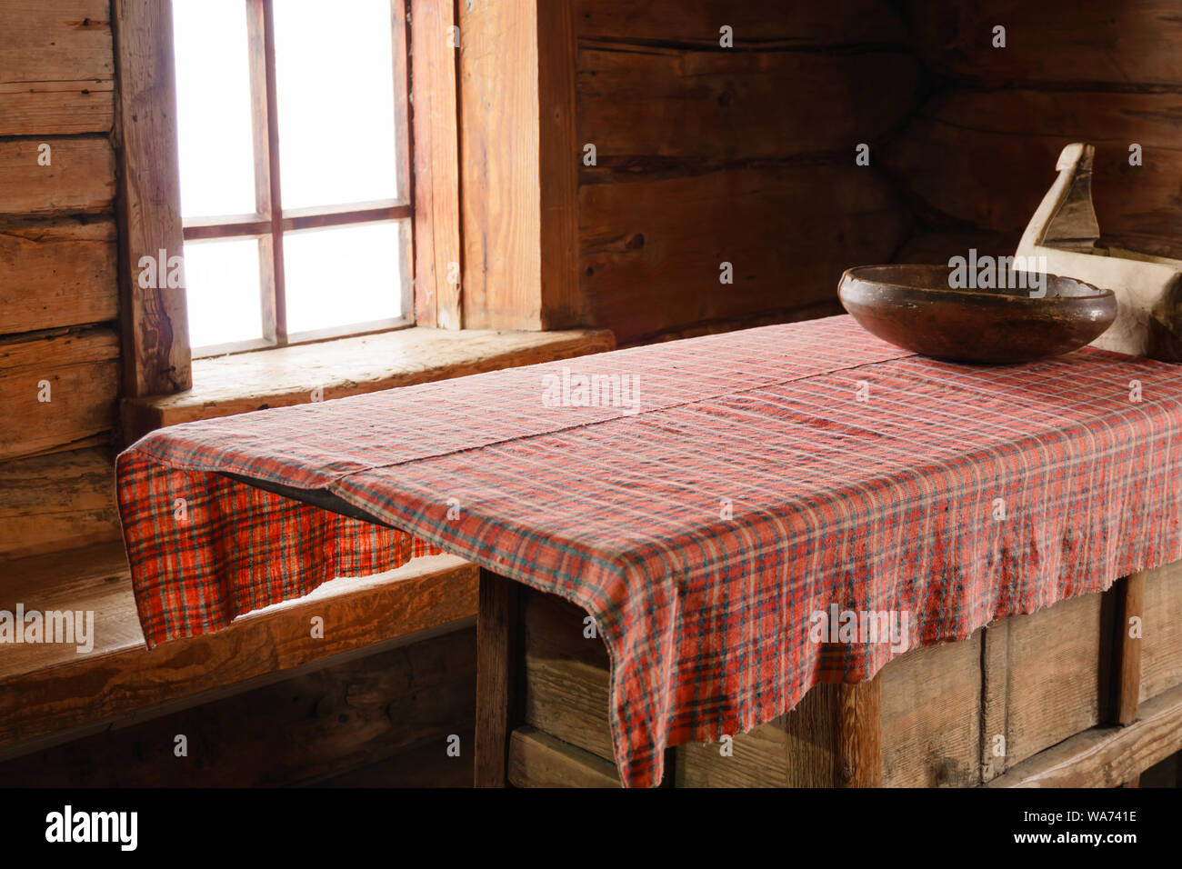 Fragment de l'intérieur d'un vieux paysan log cabin - une table avec des plats en bois, fait main et nappe tissée Banque D'Images