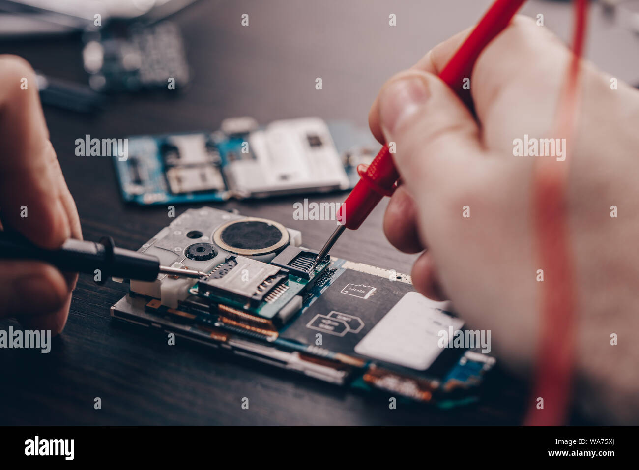 Réparation de téléphone mobile, mains libre sur une table en bois Banque D'Images