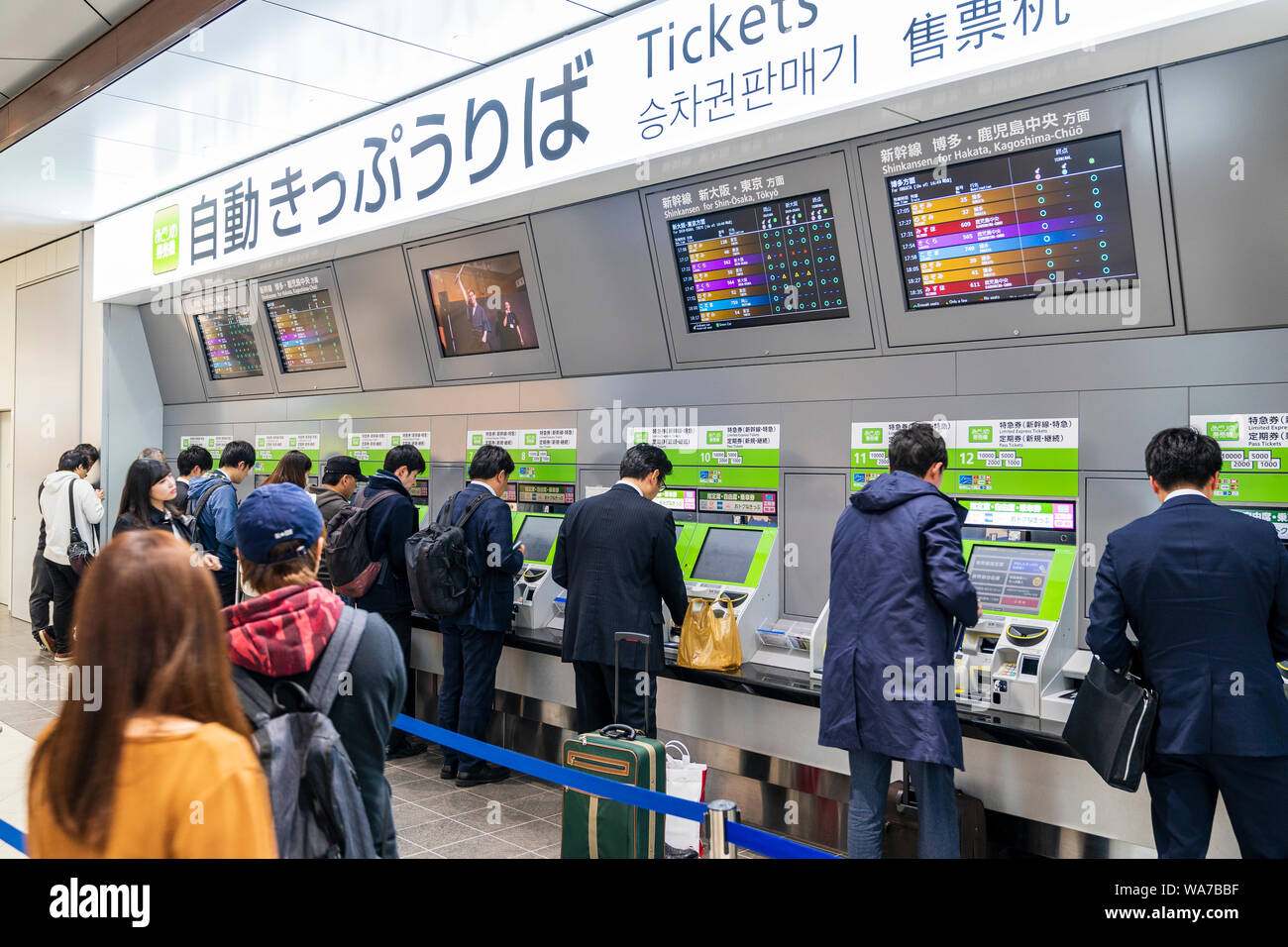 La gare d'Hiroshima, le Japon de l'intérieur. Personnes en ligne pour acheter du Shinkansen, le train à grande vitesse, de billets. Les écrans d'affichage en hauteur avec des horaires de train. Banque D'Images