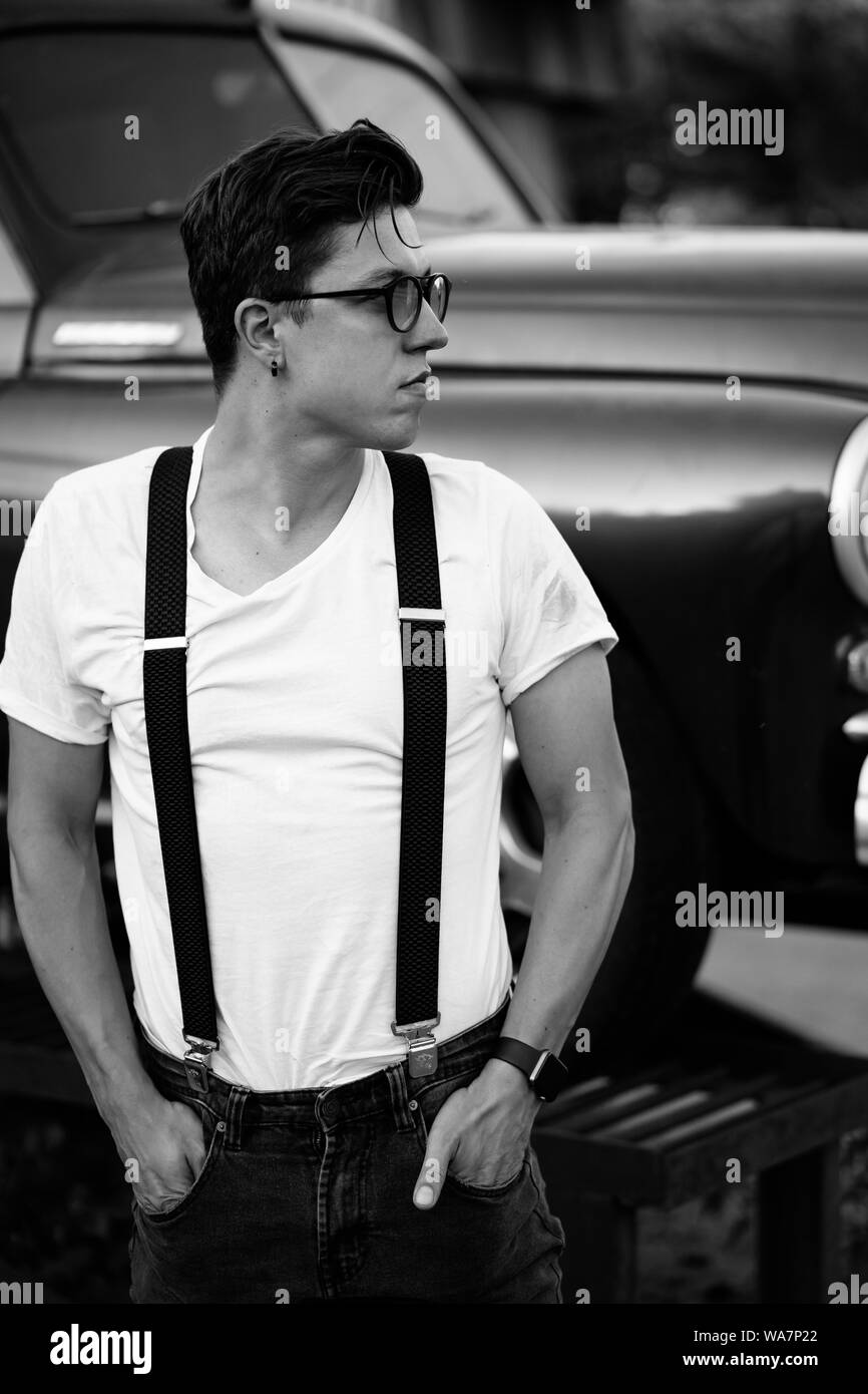 Old-fashioned hipster guy dans une chemise avec bretelles posant à la  voiture rétro Photo Stock - Alamy