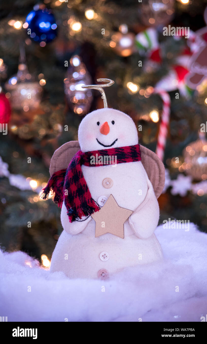 Angel bonhomme sourire alors qu'il est détenteur d'une étoile en face d'un arbre de Noël éclairé Banque D'Images