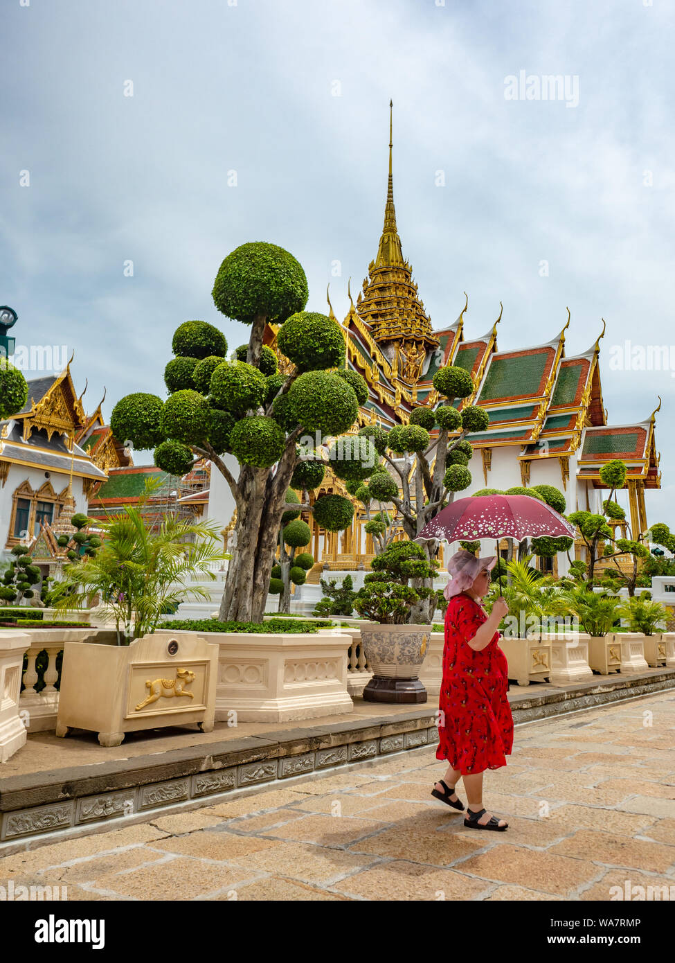 Bangkok, Thaïlande - juin 2019 : une femme asiatique non identifiée en rouge, tenant un parapluie, visite du Palais Royal Banque D'Images Bangkok, Thaïlande - juin 2019 : une femme asiatique non identifiée en rouge, tenant un parapluie, visite du Palais Royal Banque D'Images