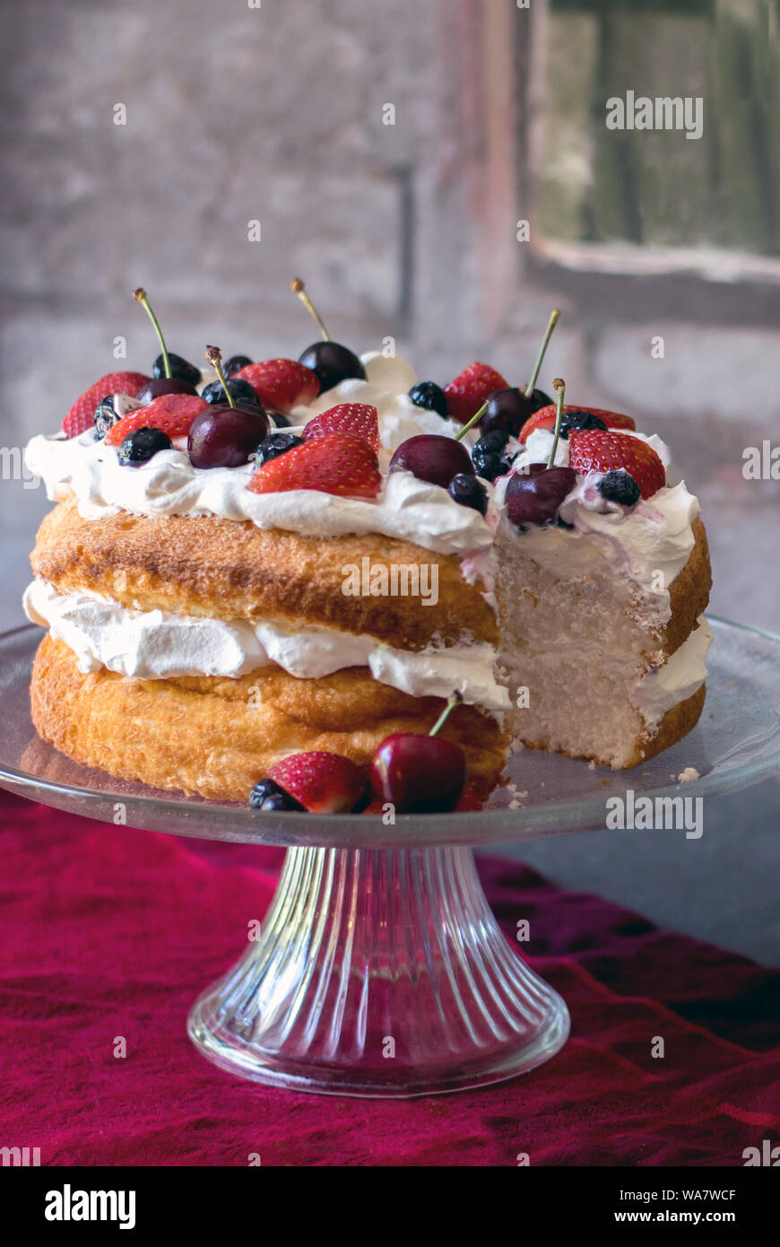 Belle angel food cake recouvert de crème fouettée et de fruits colorés frais Banque D'Images