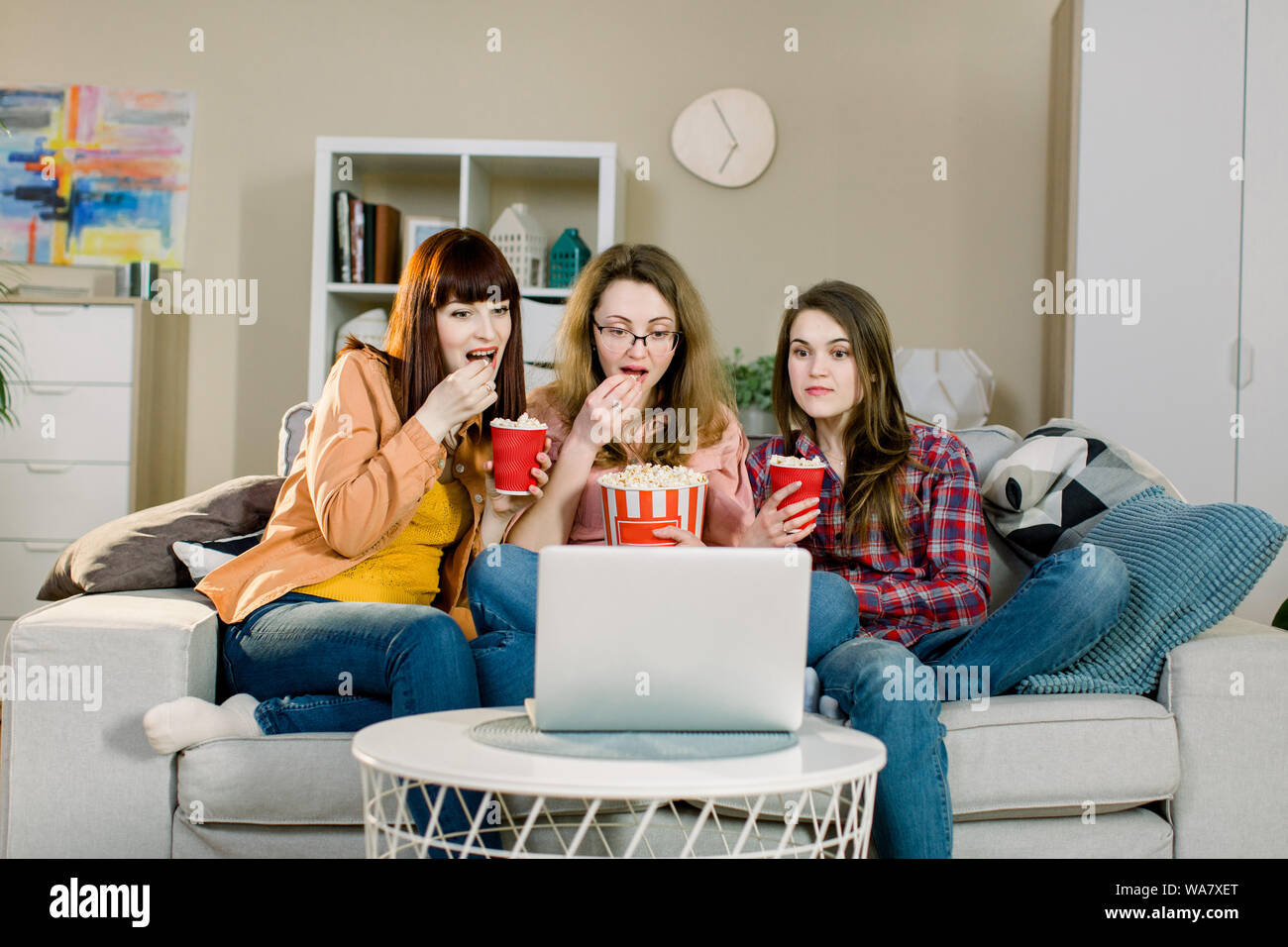 La nourriture et les films. Trois sœurs assez émotionnelle eating popcorn lorsque vous regardez des film ou programme sportif tout en s'assied sur le canapé de belle chambre à la maison Banque D'Images