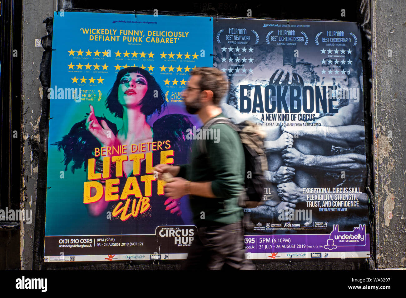 Un jeune homme marchant par affiches publicitaires pour Edinburgh Fringe Festival montre. Edinburgh, Ecosse, Royaume-Uni. (With motion blur) Banque D'Images