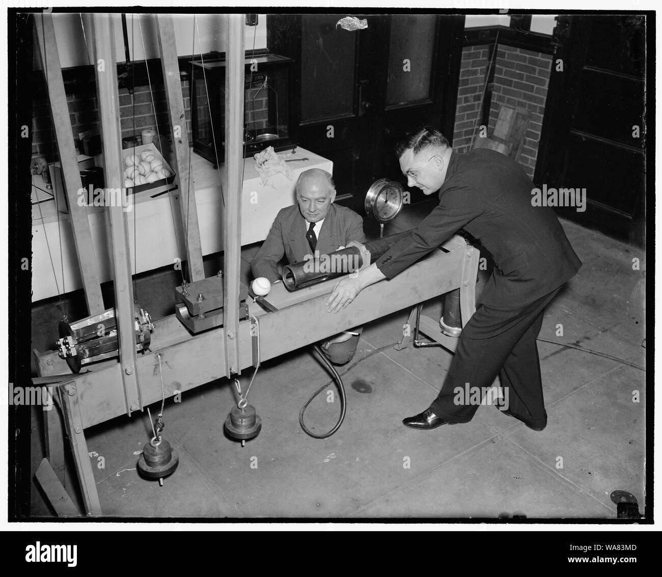 Bureau of Standards conçoit la pâte mécanique pour déterminer l'animation de base-ball. Washington, D.C., le 21 février. À l'aide d'un appareil de conception nouvelle, le U.S. Bureau of Standards aujourd'hui a commencé des expériences pour déterminer les qualités de home-run American, national et international de baseball. Dans la conduite des essais un scientifique appuie sur la gâchette d'un fusil chargé avec un projectile en bois représentant le ninja Painter's bat. Le projectile frappe une balle de baseball à l'origine de voler vers une pendule balistique. Après chacun de ces hits le scientifique prend une lecture sur la pendule. Il lui dit comment dur Banque D'Images