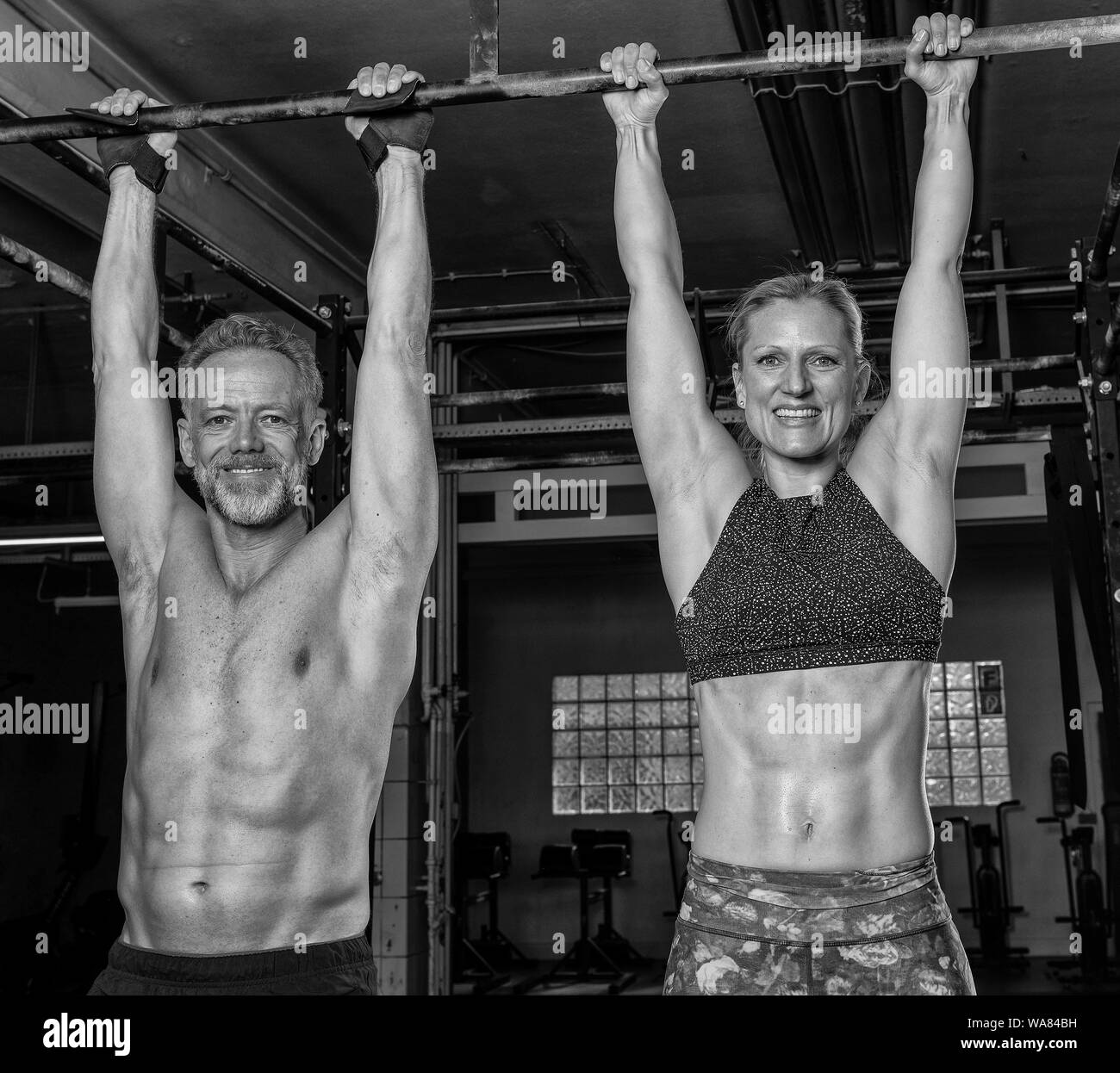 Un joli couple d'âge moyen est en train de faire une formation de remise en forme et d'avoir du plaisir ensemble. Athletic homme et une femme âgés se sont accrochés sur la barre horizontale. Banque D'Images