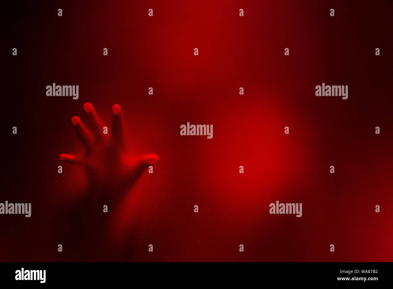 Couleur rouge version filtre de Creepy homme tenant le verre dépoli d'une main. Banque D'Images