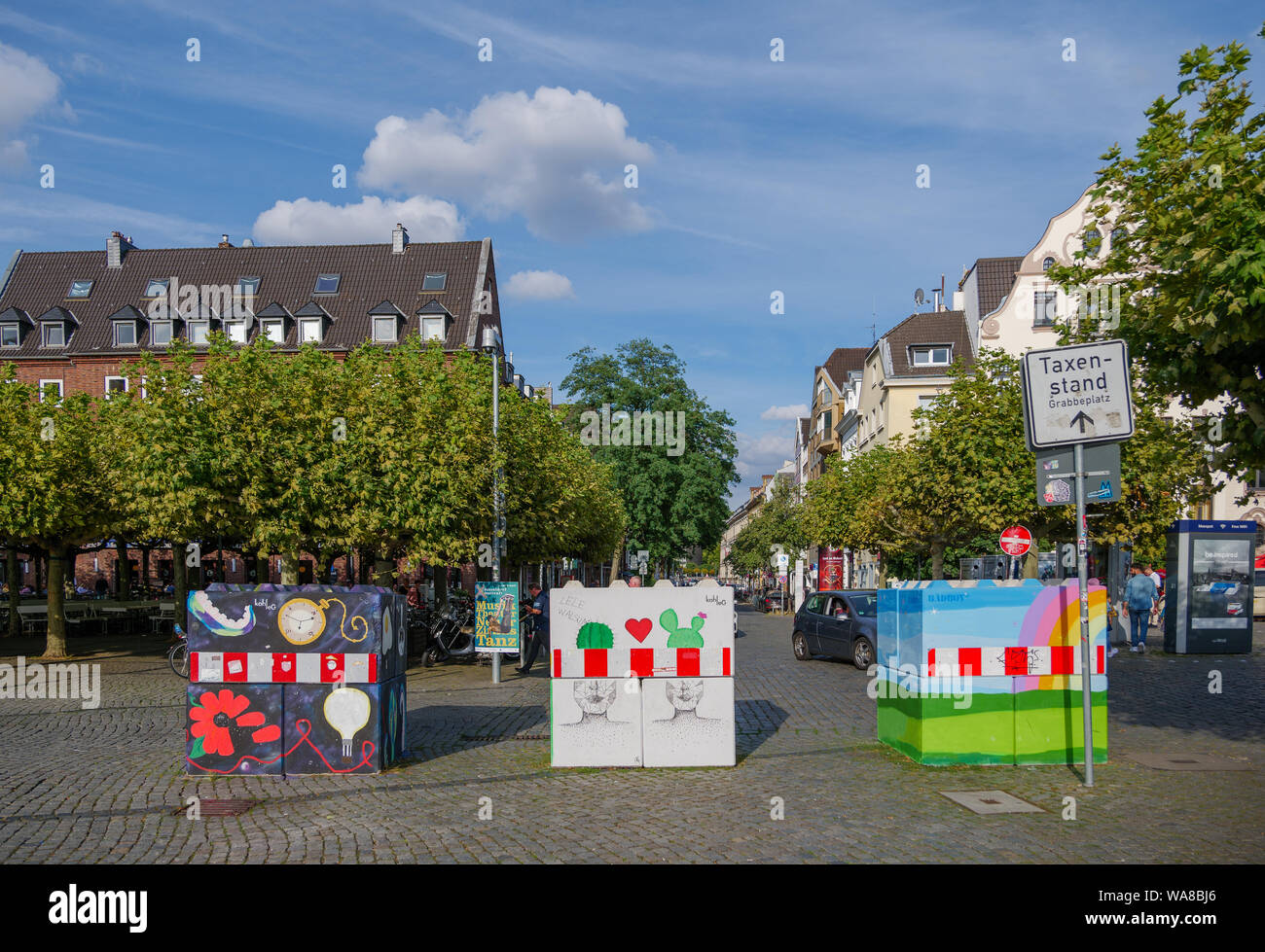 Graffitis colorés peints sur des bornes de béton ou blocs de barrières pour protéger d'attaques terroristes, situé au Burgplatz, dans la vieille ville de Düsseldorf. Banque D'Images