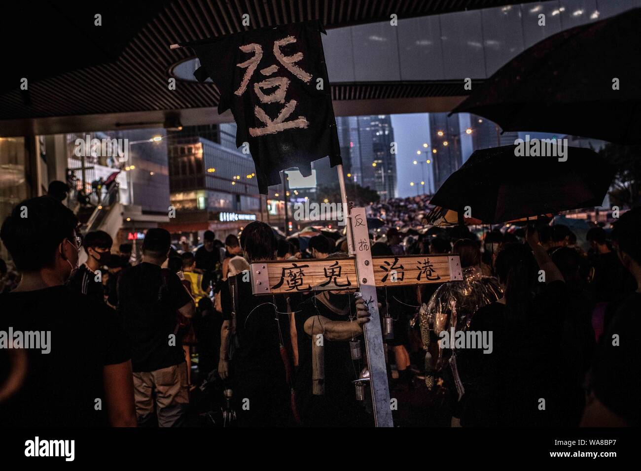 Un manifestant est titulaire d'une croix en bois avec l'inscription "le mal régit Hong Kong' pendant la démonstration.Les manifestants sont descendus dans la rue sur un dimanche pluvieux dans une manifestation pro-démocratie sur l'île de Hong Kong, ils exigent le retrait complet de la loi sur l'extradition et le gouvernement à mettre en place une enquête indépendante sur les récents affrontements entre manifestants et policiers - Les organisateurs ont déclaré que c'était le plus grand rassemblement au cours de la semaine. Banque D'Images