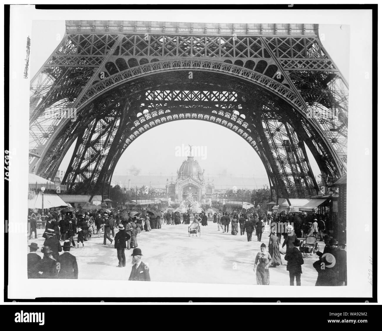 Coupole centrale et la fontaine Coutan vu à travers la base de la Tour Eiffel, avec foule sur le Champ de Mars, l'Exposition de Paris, 1889 Banque D'Images