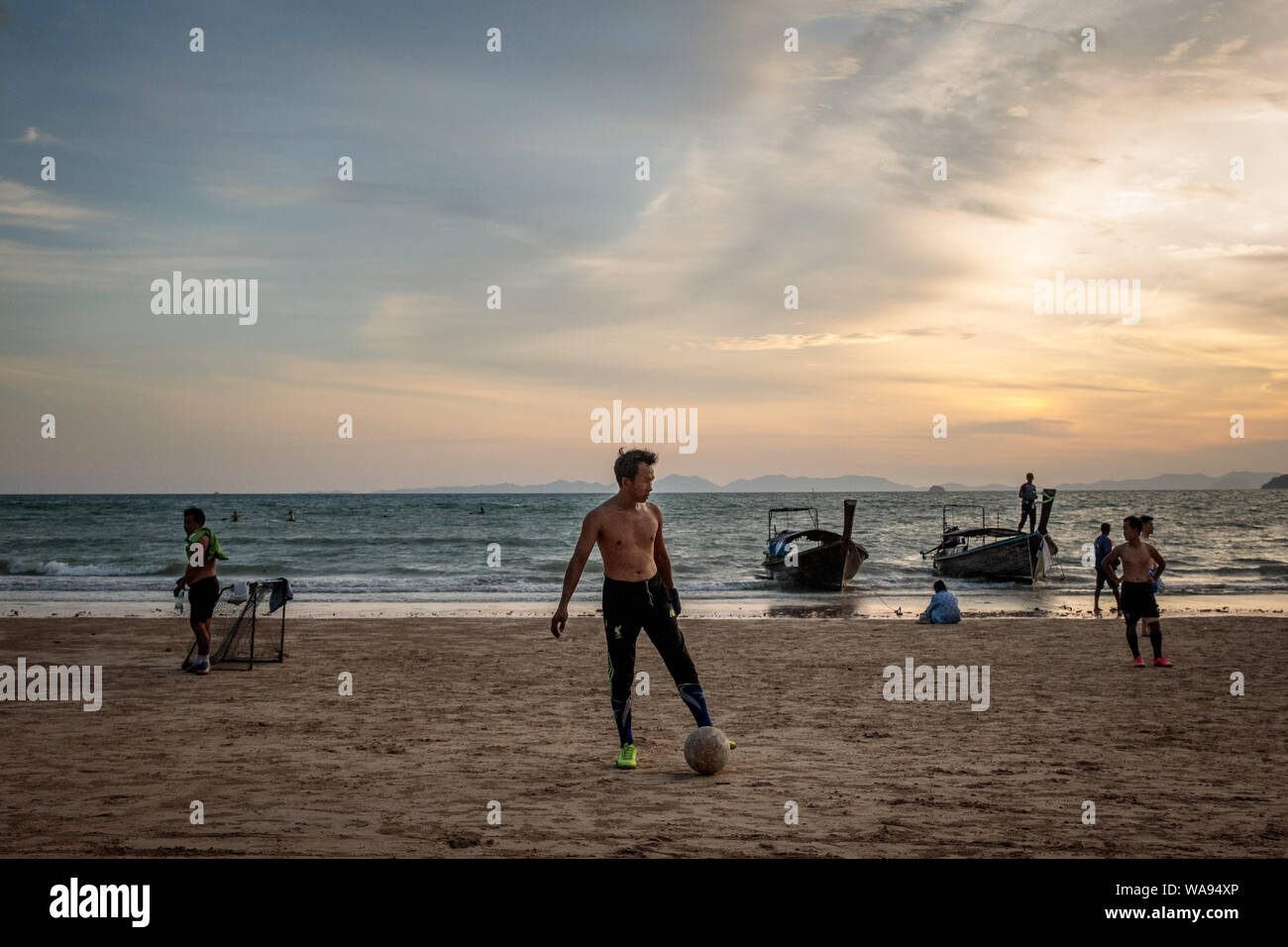 Un groupe de jeunes hommes jouent au football sur le sable sur la plage de West Railay au coucher du soleil, de Krabi en Thaïlande en juillet 2019. Banque D'Images