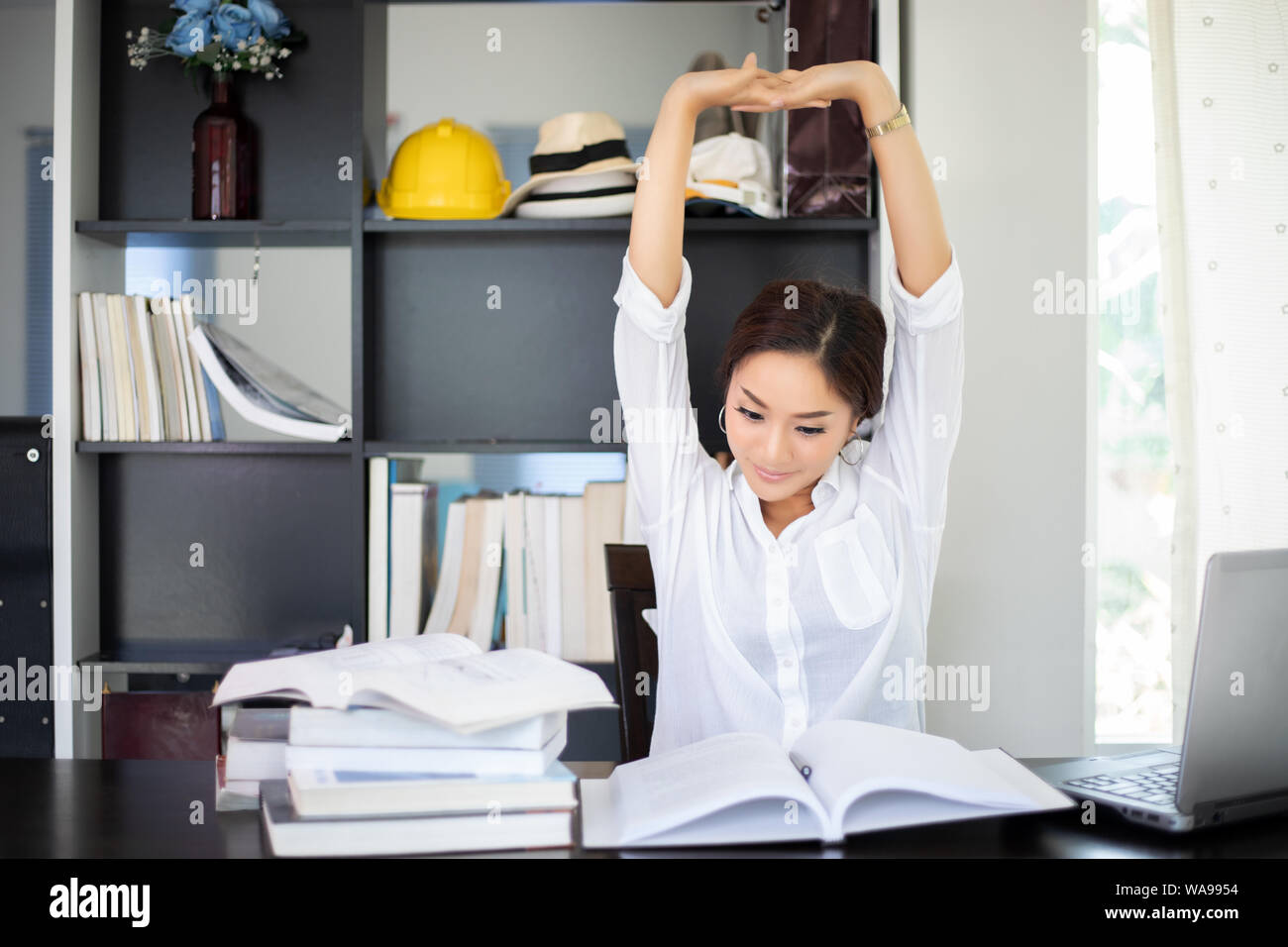 Asian woman stretching après la lecture de livre et travailler fort et souriant dans le home office Banque D'Images