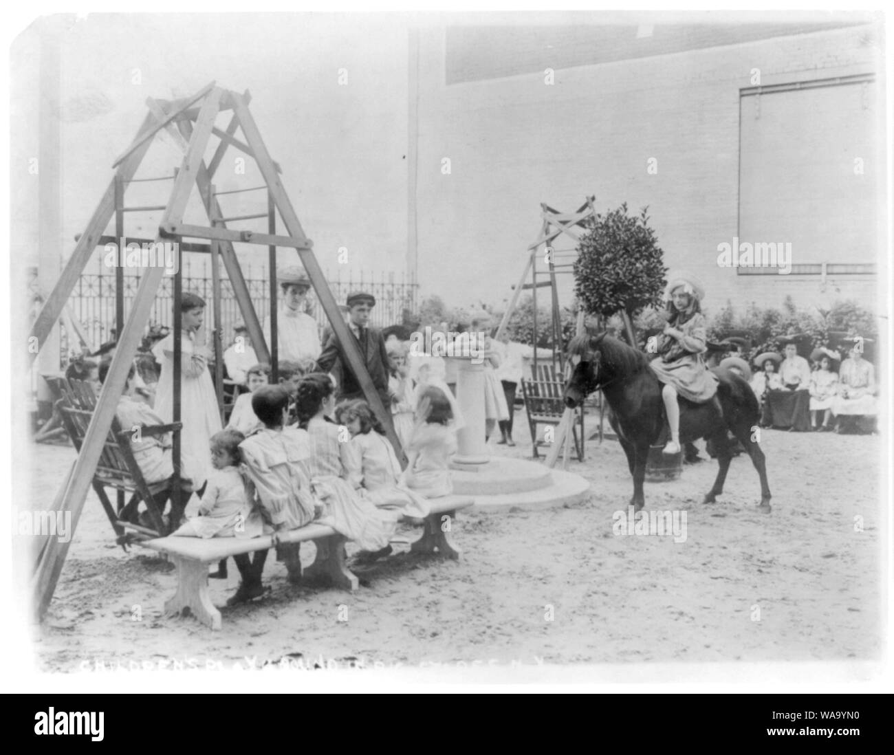 Aire de jeux pour enfants sur le toit d'un grand magasin de New York alors que les mères sont shopping ; poney et balançoires Banque D'Images