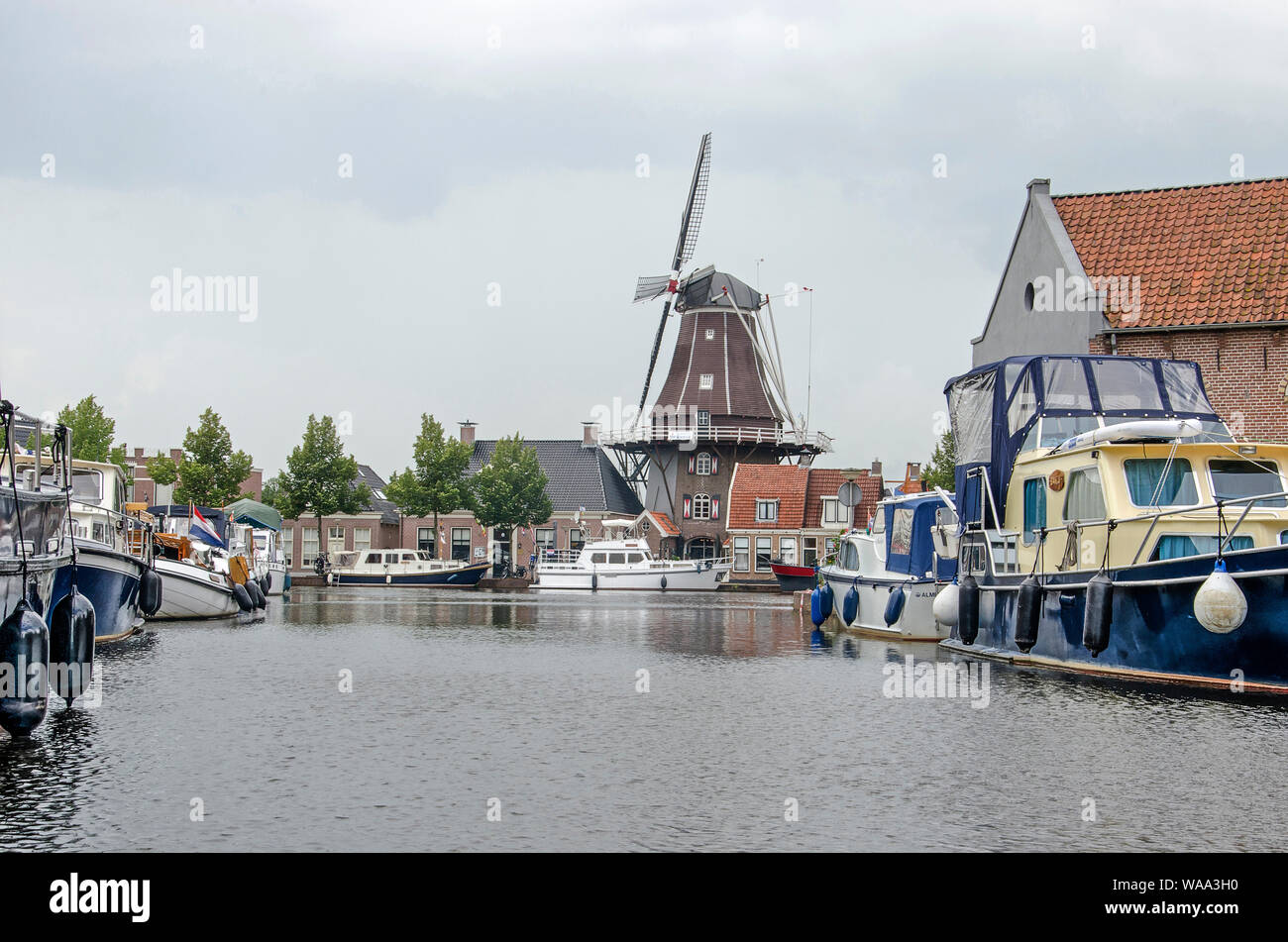Meppel, aux Pays-Bas, le 1 août, 2019 : voir le long d'un canal avec yachts amarrés sur deux côtés vers moulin traditionnel De Onderneming, sous un ciel nuageux Banque D'Images