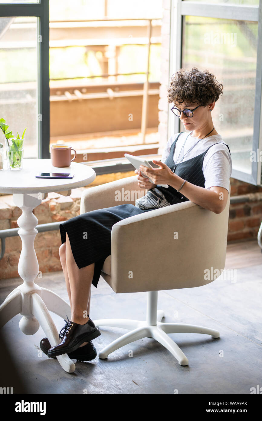 Jeune femme casualwear reposant dans le défilement dans digital tablet Banque D'Images