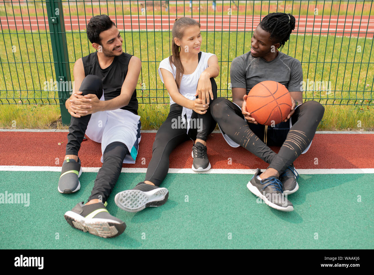 Deux gars et une fille dans les vêtements de sport tout en restant assis sur le chat jeux pour enfants Banque D'Images