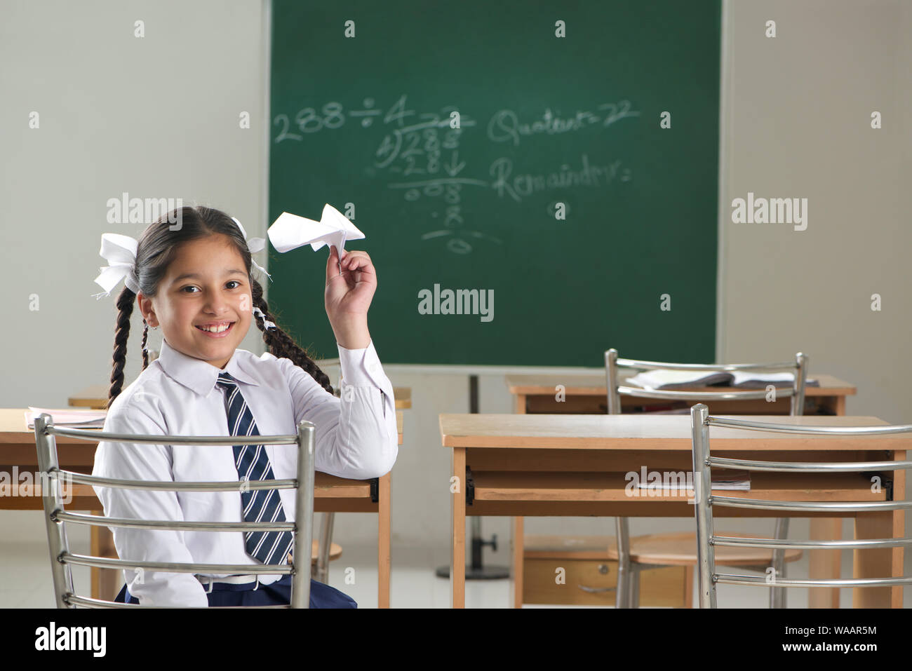 Une écolière jouant avec un avion en papier dans une salle de classe Banque D'Images