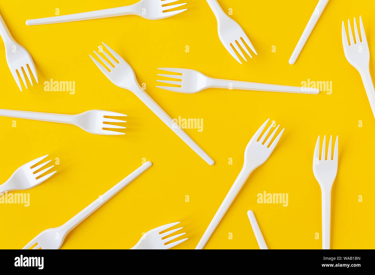 Les fourchettes en plastique blanc sur fond jaune vif. Flatlay. Restauration rapide, eco et pas de concept en plastique. Ouvrir la composition. Banque D'Images