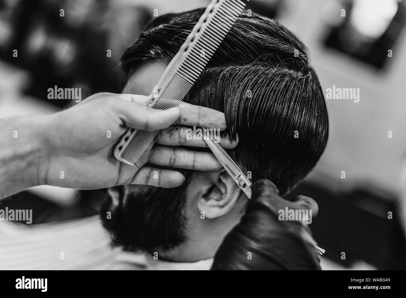 Recevoir des services de coiffure. Coupe de cheveux pour les hommes. Coupe de cheveux avec des ciseaux. Photo en noir et blanc. Banque D'Images