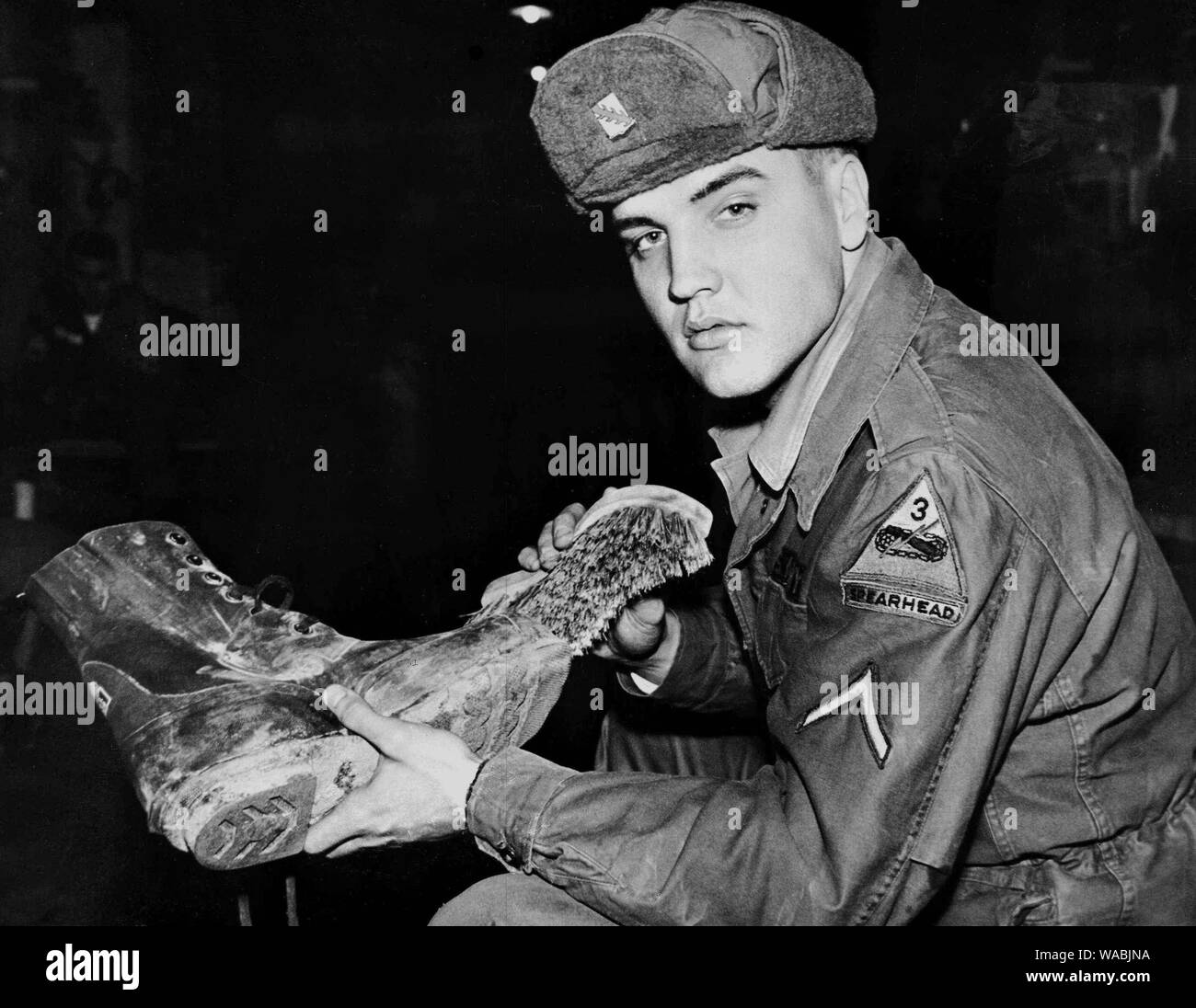 Elvis Presley, en uniforme, nettoie ses bottes à la base d'entraînement Grafenwoehr en Bavière, Allemagne (1958) #  de dossier 33848-390THA Banque D'Images