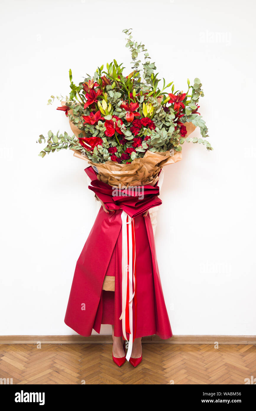 Belle jeune femme blonde holding big bouquet de fleurs colorées contre le mur blanc Banque D'Images