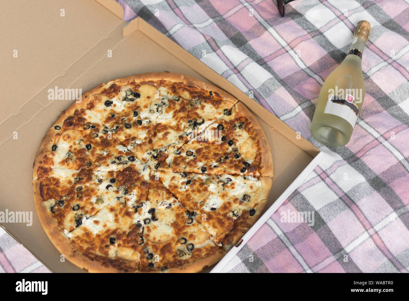 Pizza dans une boîte en carton Vue de dessus et une bouteille de champagne. Livraison de pizza. Concept de pique-nique. Banque D'Images