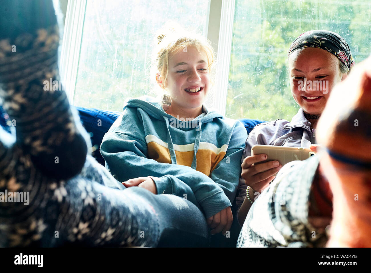 Les jeunes filles assis sur un canapé en regardant un écran et de rire Banque D'Images