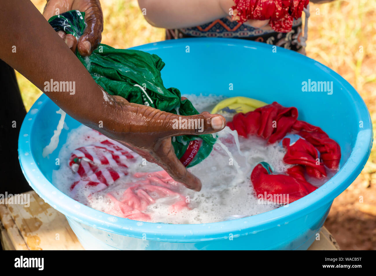 Nanyuki, Kenya - Juin 13th, 2019 : photographie en couleur de kényane le lavage en blanchisserie bol bleu avec seulement les mains visibles. Banque D'Images