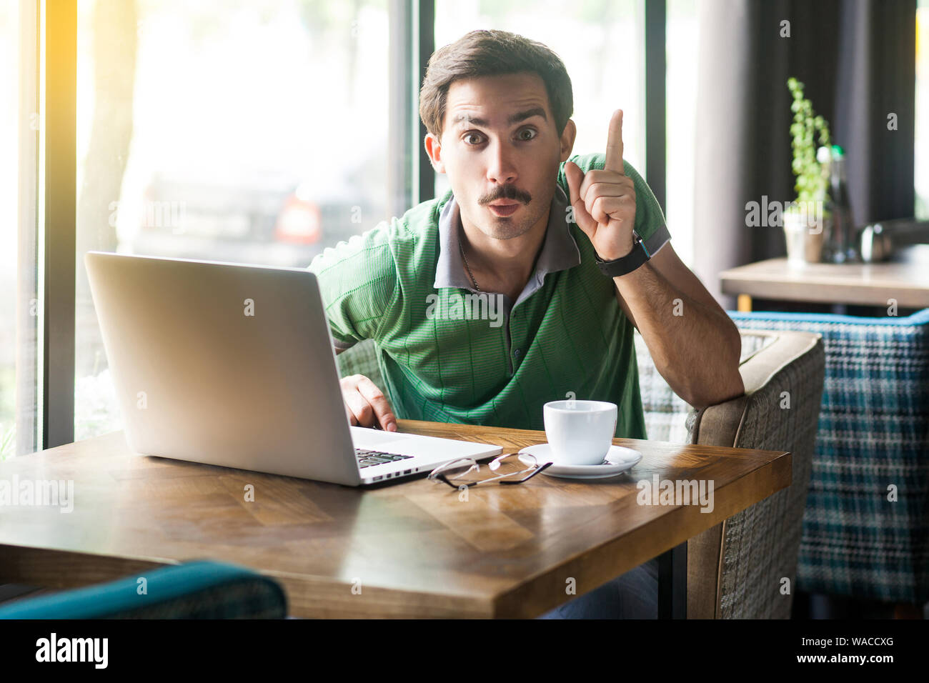 Oh, j'ai une idée ! Jeune homme surpris en t-shirt vert assis à l'idée de geste et de visage excité. entreprise et freel Banque D'Images