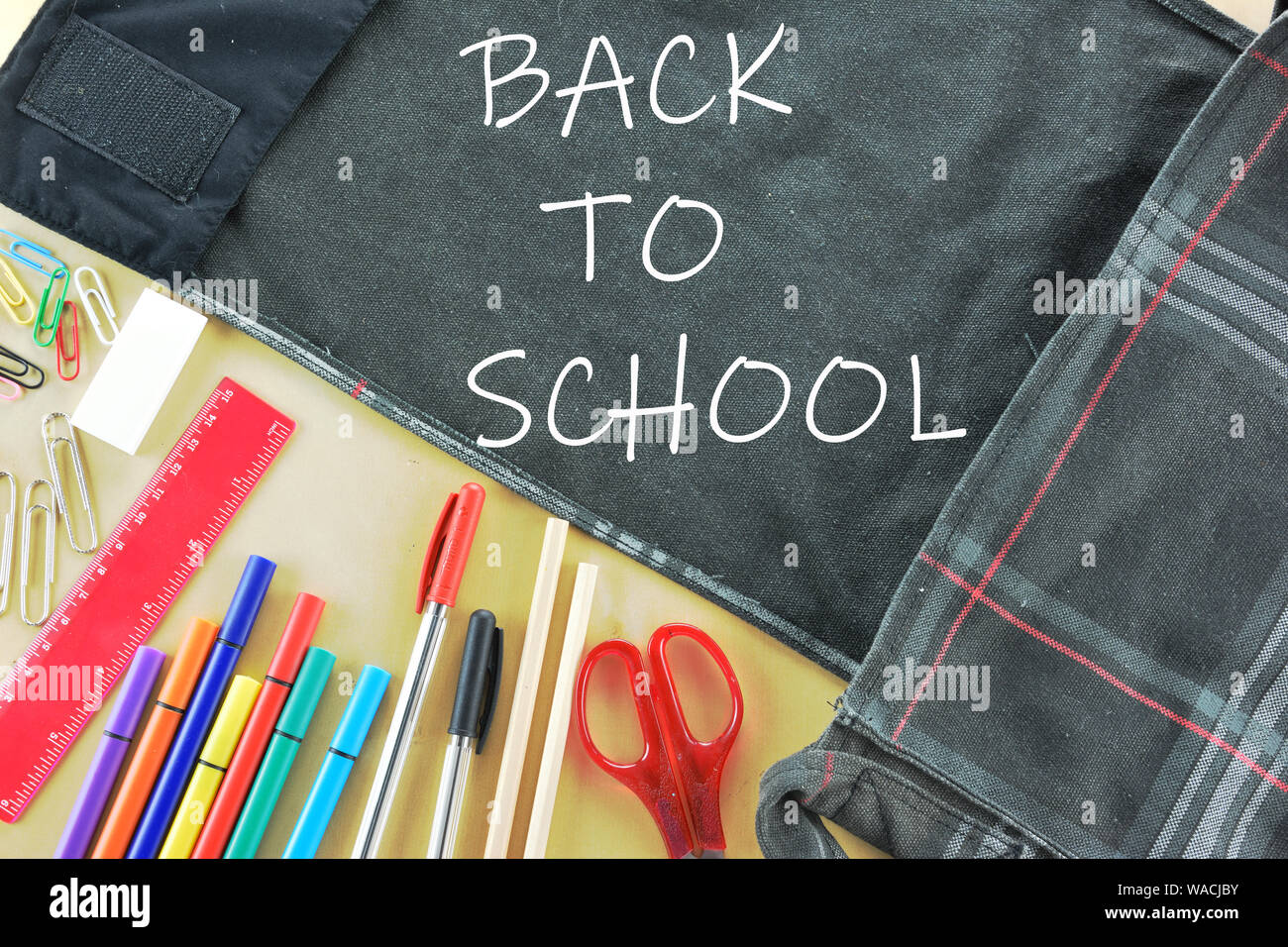 Concept Retour à l'école avec un sac et des fournitures scolaires sur fond de bois Banque D'Images
