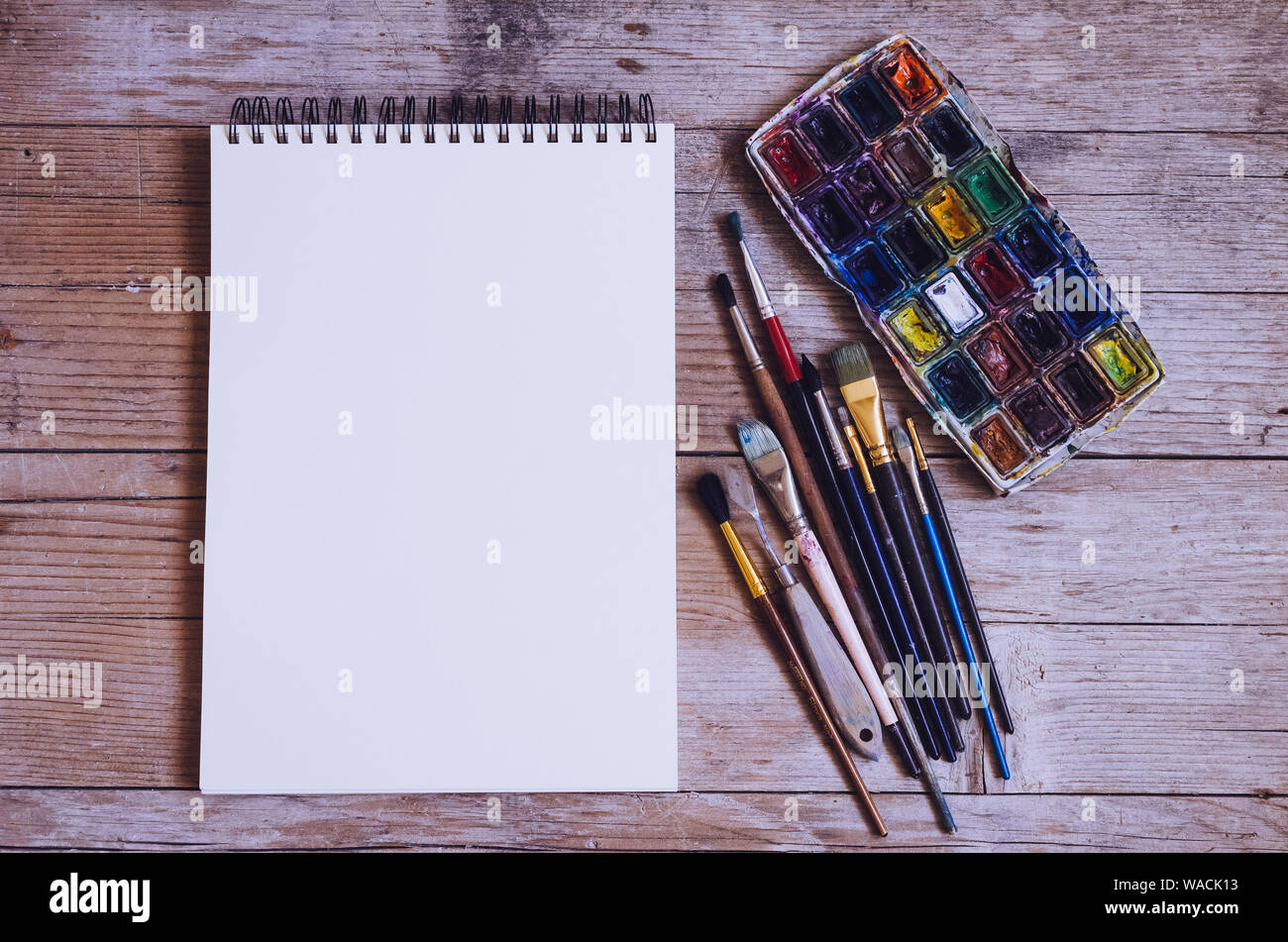 Artiste Créateur de travail télévision lay, immersive. Vue de dessus sur table avec carnet vierge, pinceaux et palettes de colorant. L'Art, atelier, peinture, dessin, Banque D'Images