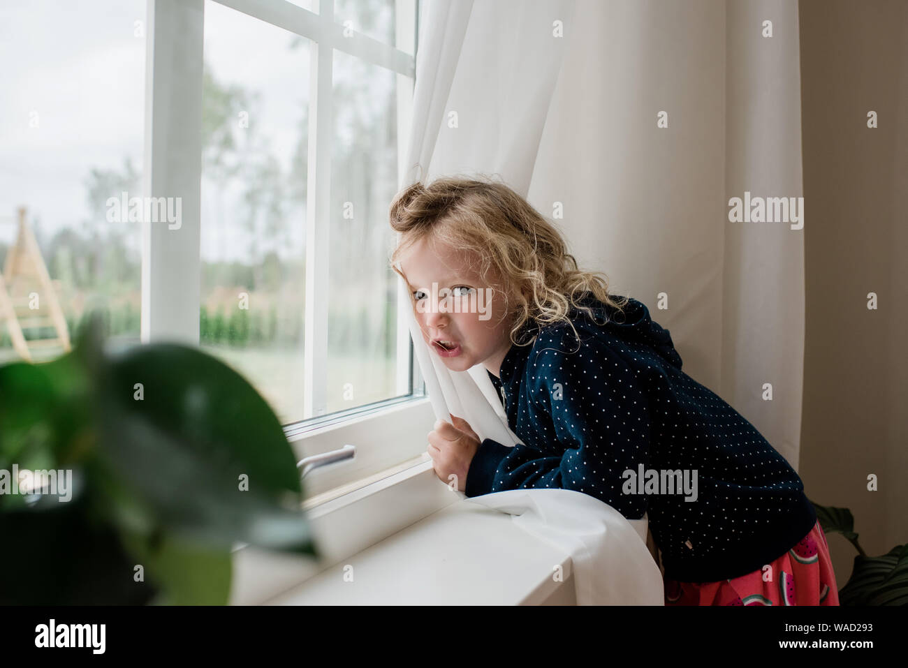 Portrait of a Girl appuyé contre une fenêtre scowling Banque D'Images