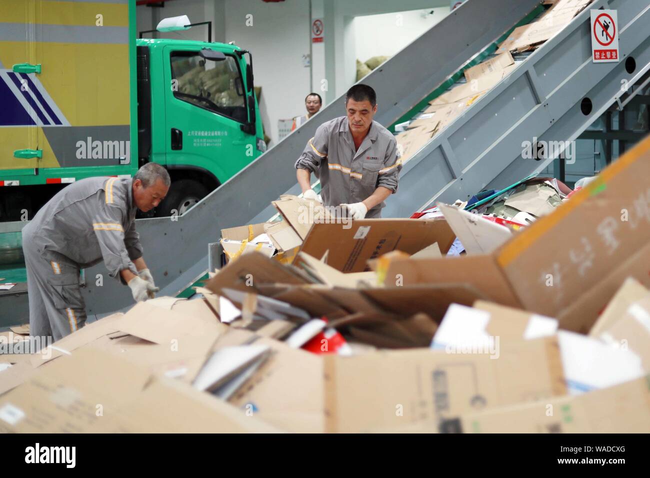 Un travailleur chinois sortes de recyclage des déchets à un centre de distribution d'énergies renouvelables à partir des déchets collectés déployée pour répondre à la nouvelle tri déchets s Banque D'Images