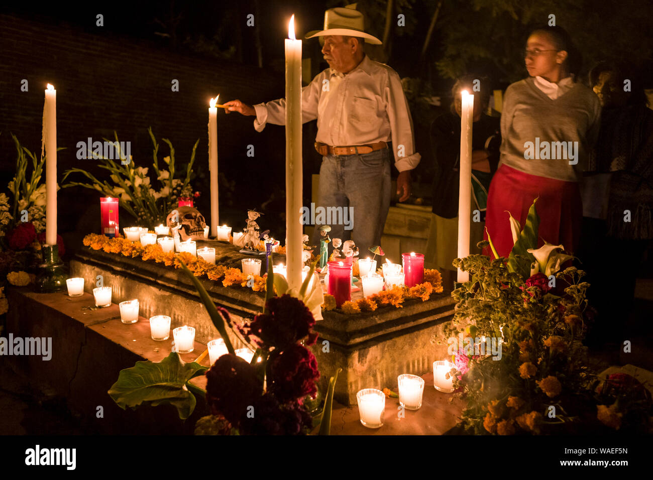 Bougies d'éclairage de l'homme au cimetière en grave décoré pour le Jour des Morts, Xoxocotlan, Oaxaca, Mexique vacances locales et festivals traditions culturelles Banque D'Images