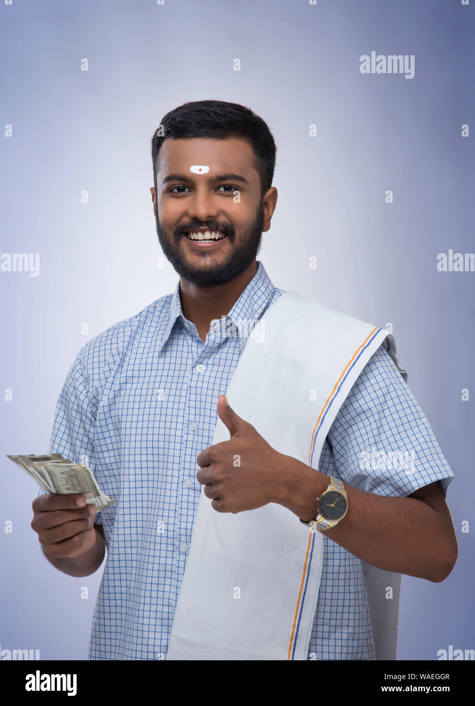 L'homme du sud de l'Inde de la détention de monnaie et smiling at the camera Banque D'Images