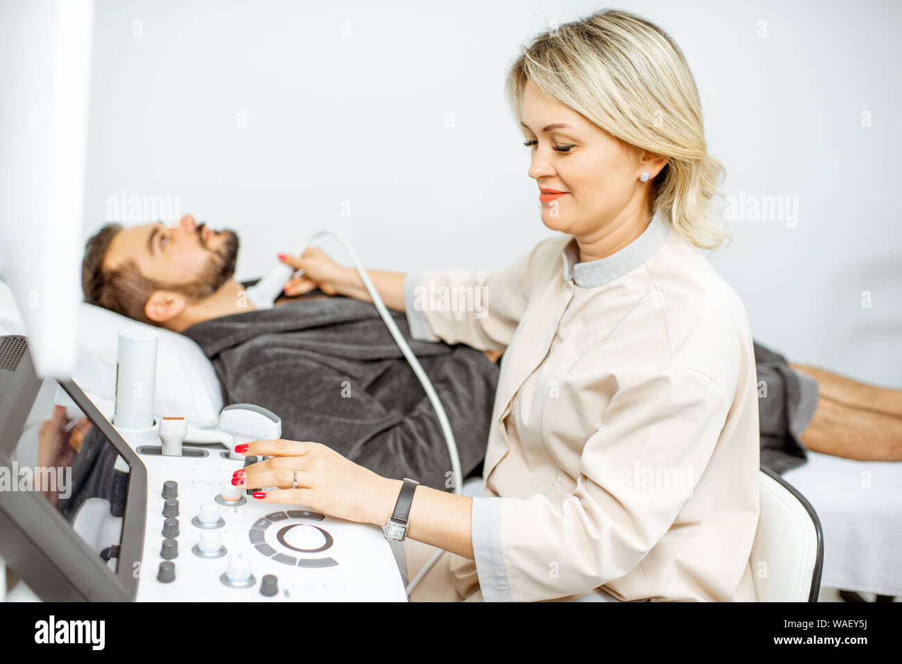 Femme médecin procède à l'examen d'ultrasons d'un men's thyroïde dans le bureau médical. Concept de diagnostic échographique de la santé masculine Banque D'Images