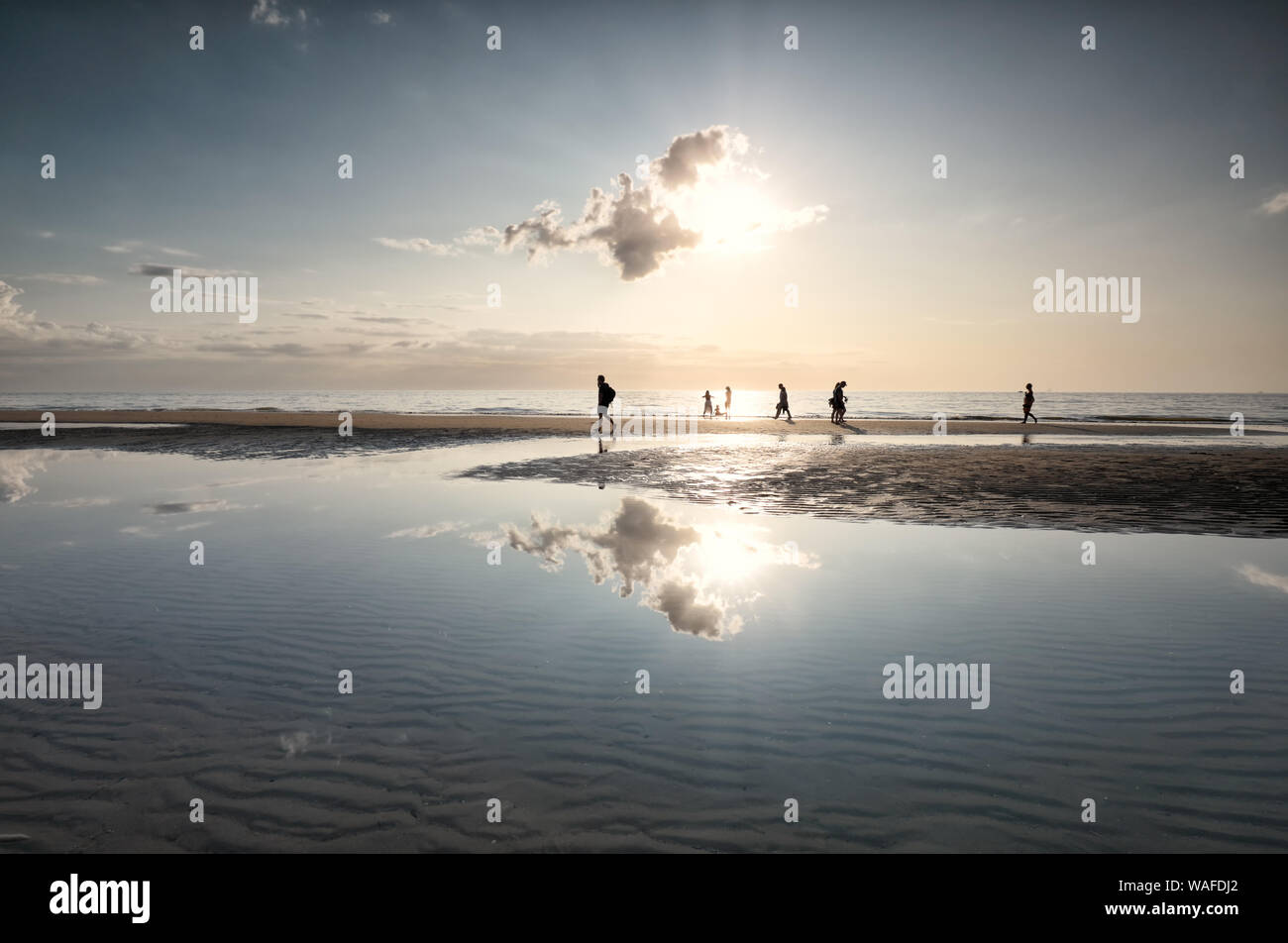 Les gens silhouettes sur mer plage contre le soleil en été Banque D'Images