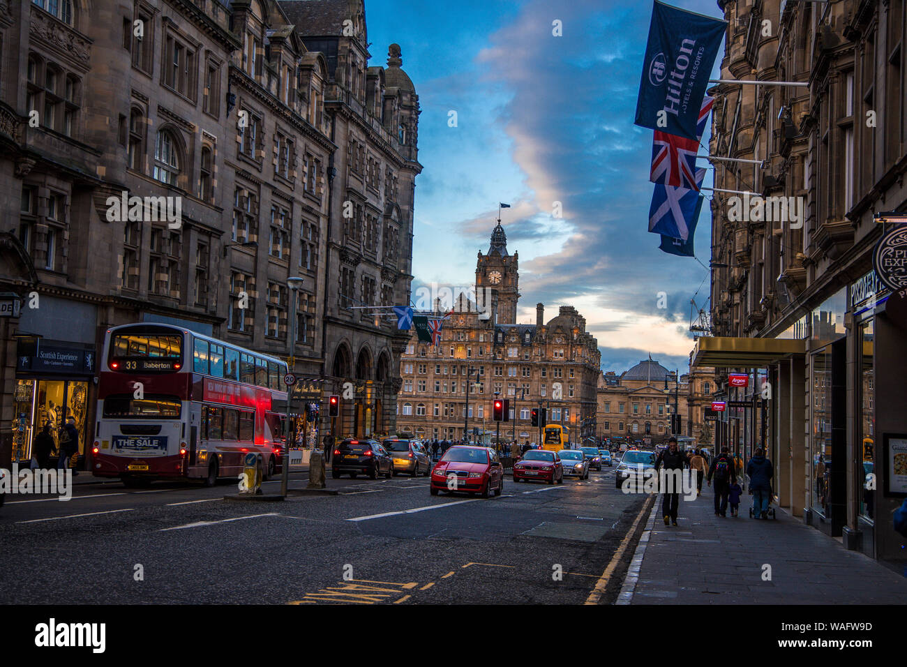 Scène de rue Moody du Royal Mile Edinburgh Scotland UK montrant Hilton hotel, vieux bâtiments, boutiques, voitures, bus et les gens plus flags Banque D'Images