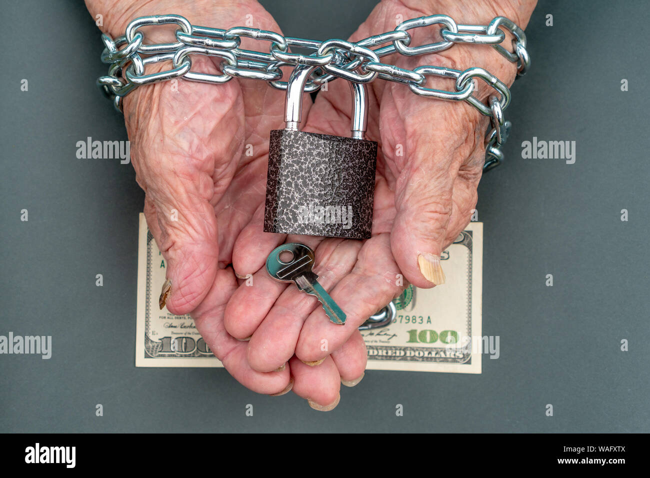 Mains d'une vieille femme 90 ans près. La clé et de la serrure, 100 dollars dans les mains d'une vieille femme. La vieille femme a les mains liées avec une chaîne. Banque D'Images