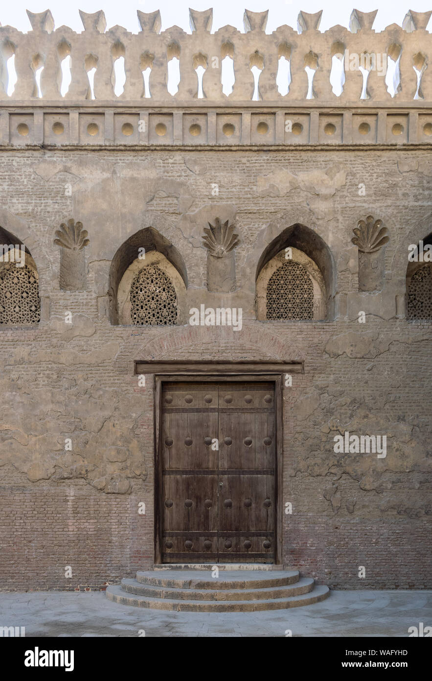 Porte en bois vieilli, voûté surmonté perforé en stuc fenêtre ornée avec  des motifs floraux, et trois étapes sur mur de briques en pierre, la  mosquée Ibn Tulun, Le Caire, Egypte Photo