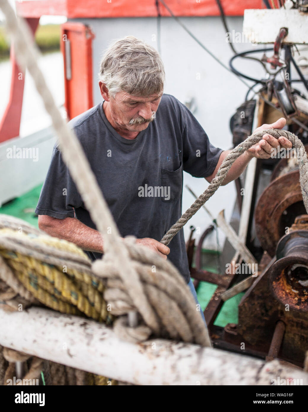Un pêcheur commercial se déplace d'une corde sur un treuil sur un bateau de pêche commerciale en Caroline du Sud. Banque D'Images