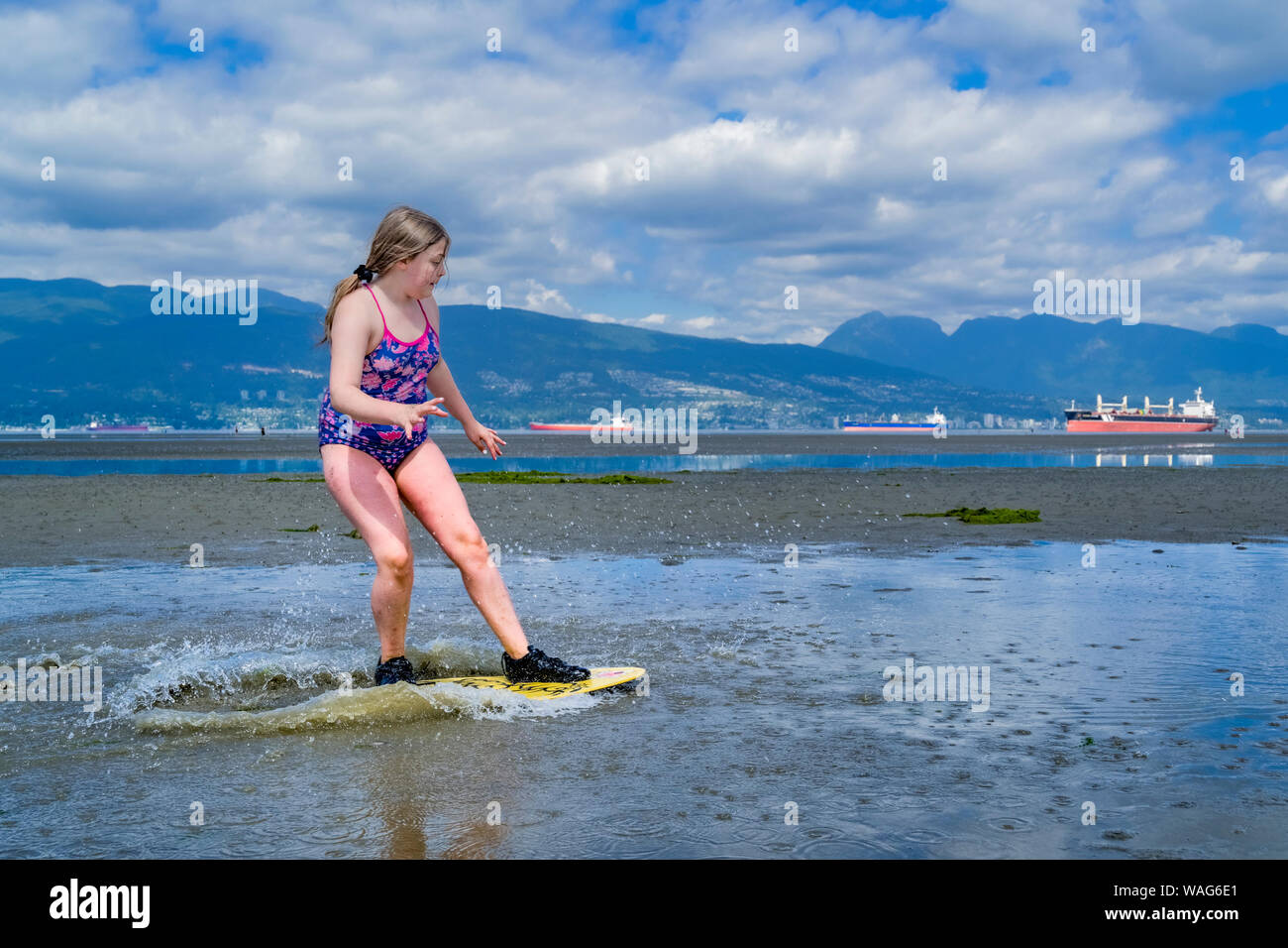 Jeune fille skimboarding, les banques espagnoles, English Bay, Vancouver, British Columbia, Canada Banque D'Images