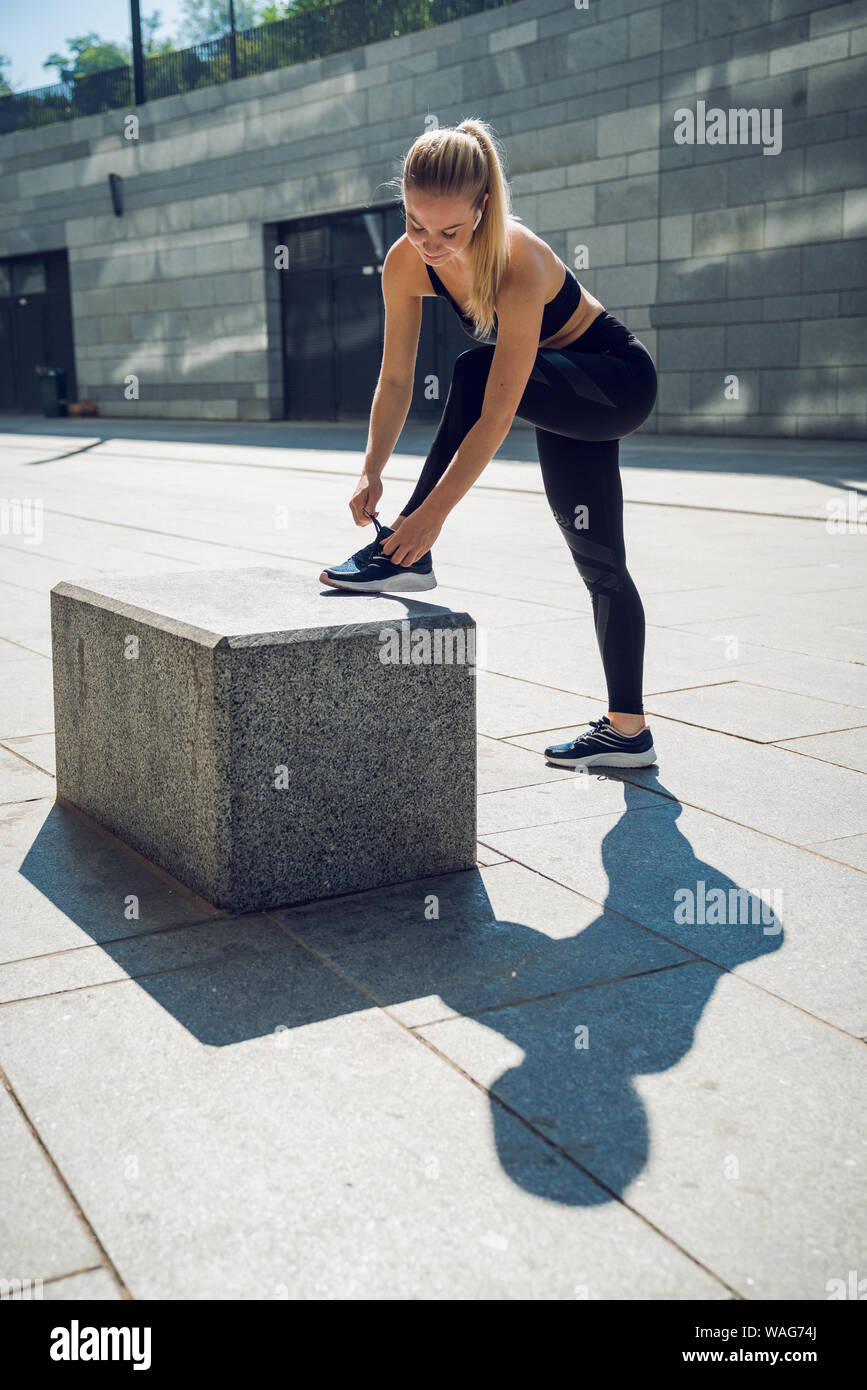 Woman in Black sportswear standing outdoors attaché la corde sur un chaussures Banque D'Images