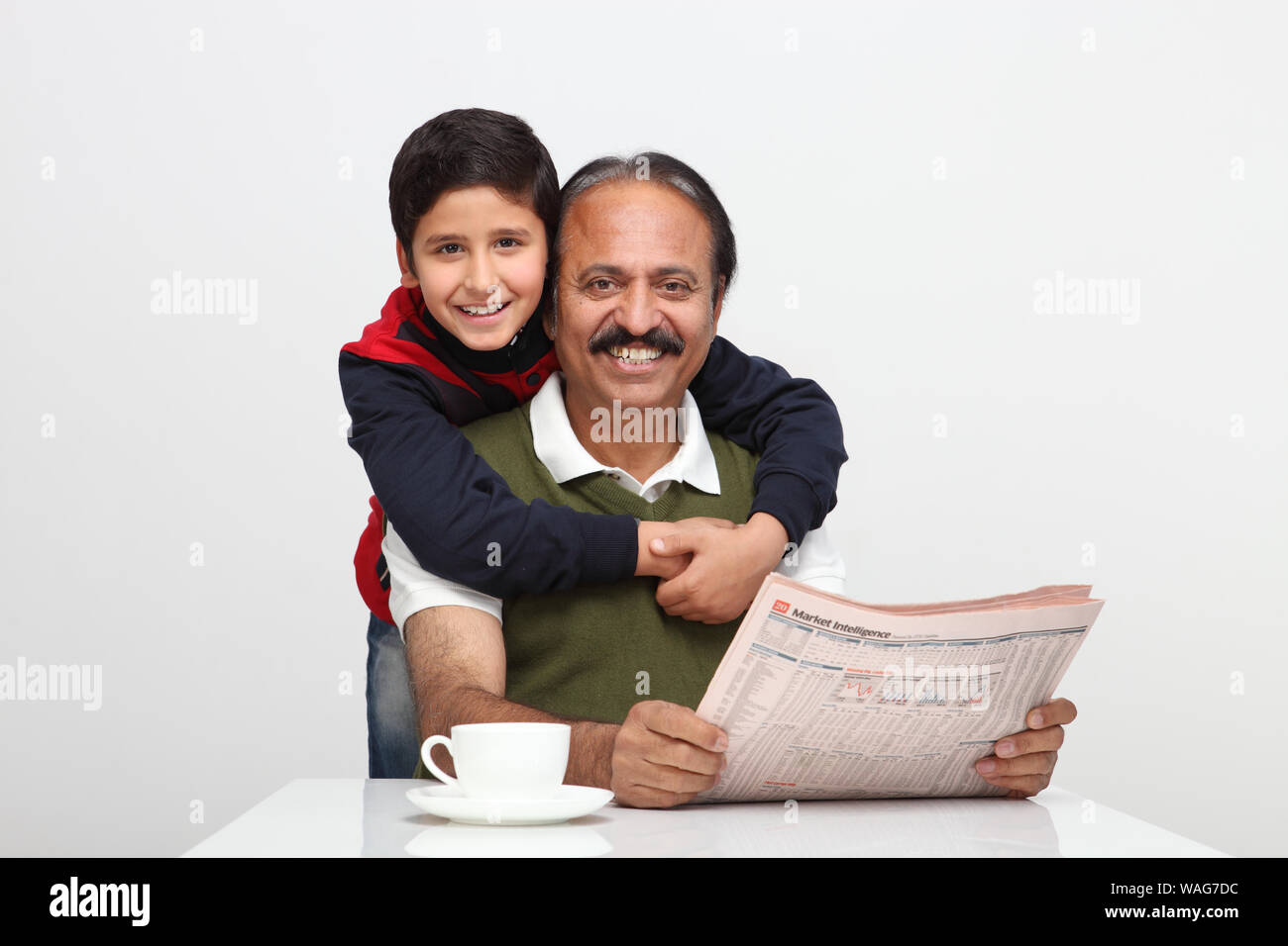 Le vieil homme lisant le journal avec son petit-fils qui s'embrasse derrière lui Banque D'Images