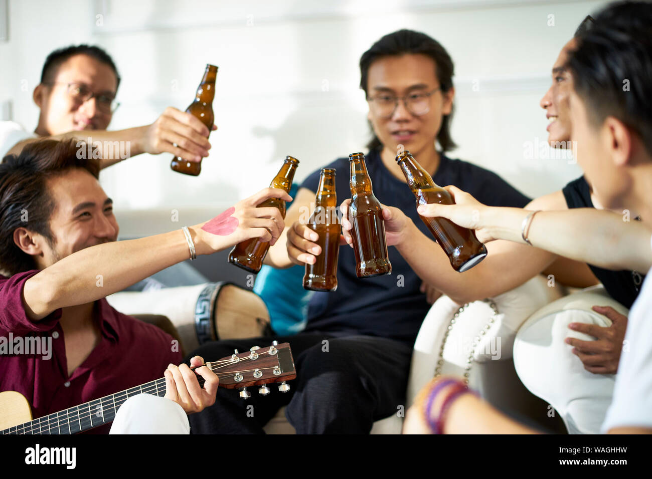 Les jeunes hommes adultes asiatiques se détendre et profiter de la musique et de la bière au travail Banque D'Images