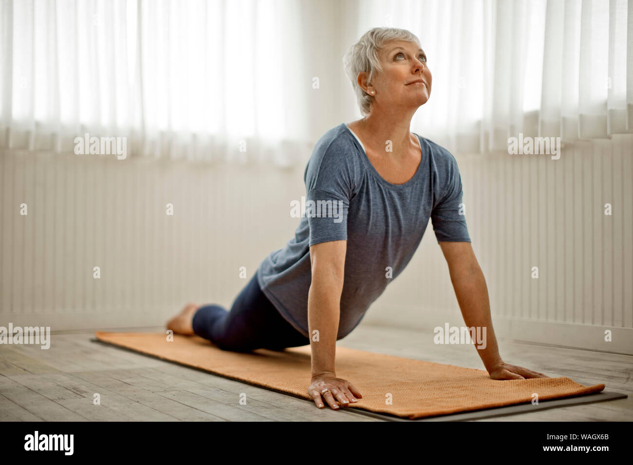 Femme mature pacifiques pratiques étirements de yoga dans son home studio. Banque D'Images